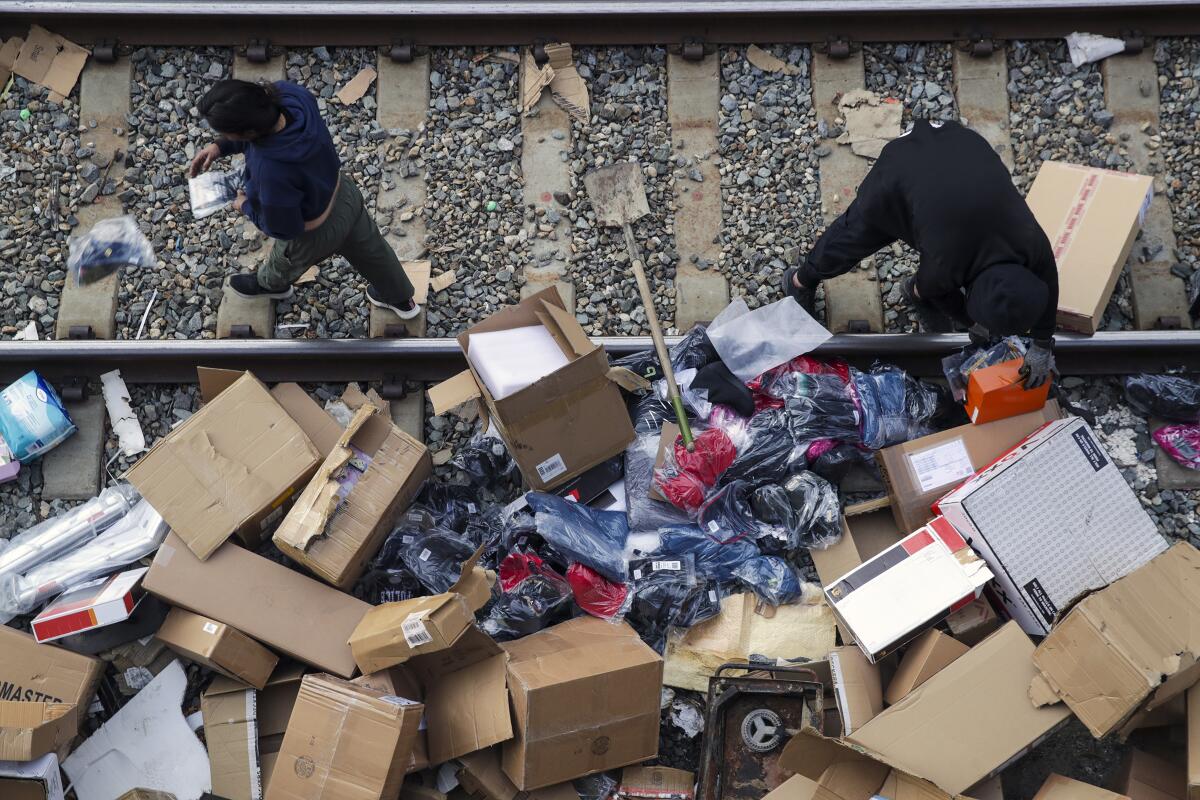 People rummage through stuff stolen from cargo containers littered on Union Pacific train tracks