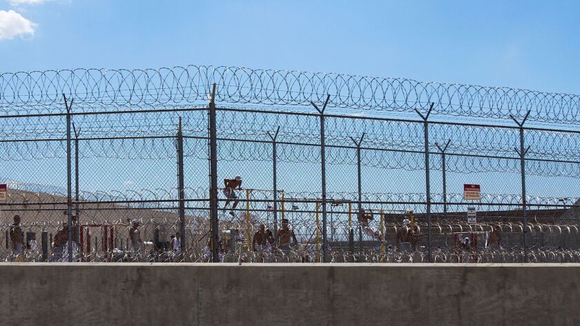 Detainees work out in the yard behind double fencing and barbed wire at the Adelanto immigration detention facility in 2014.