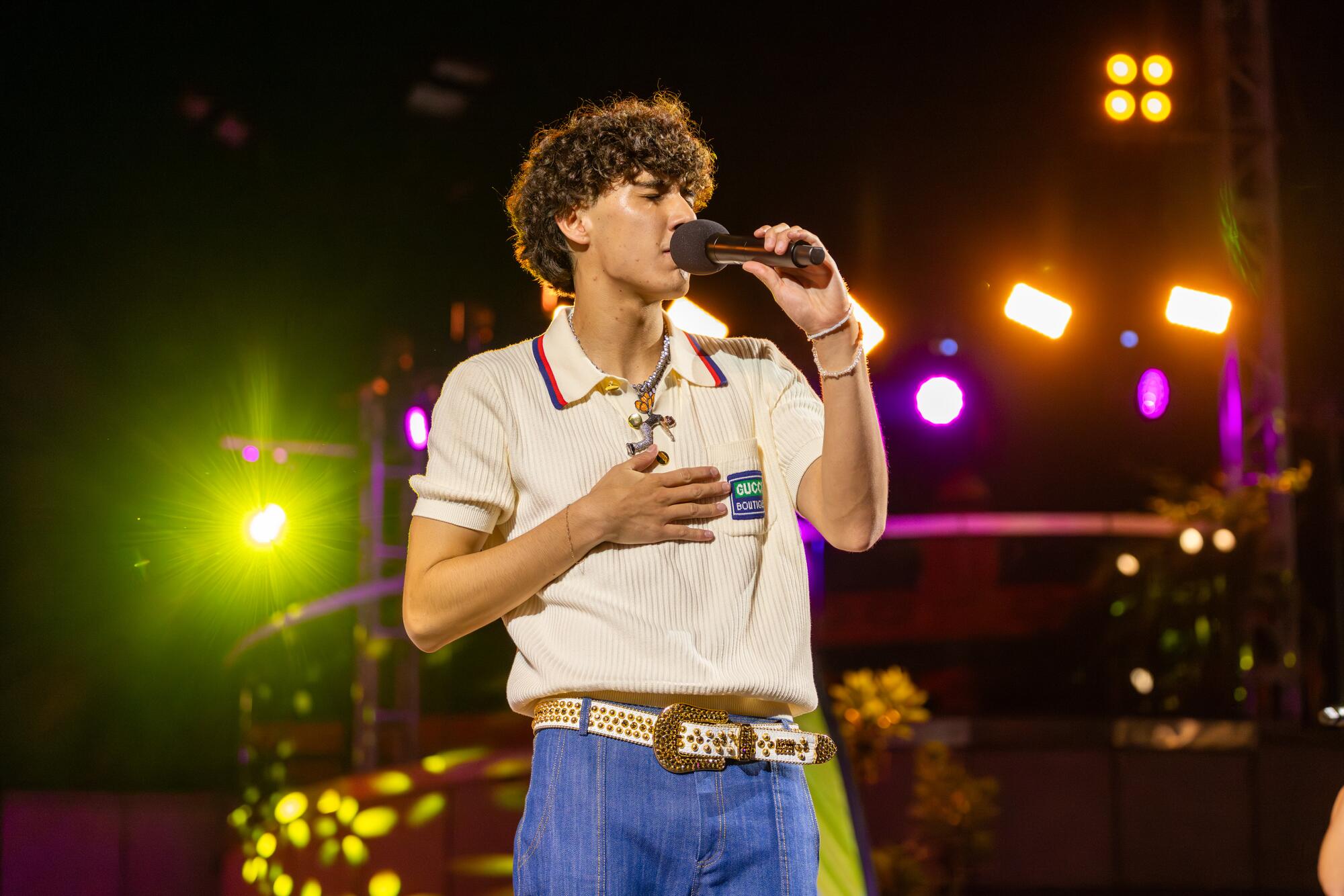 DannyLux performs onstage in a polo shirt and jeans.