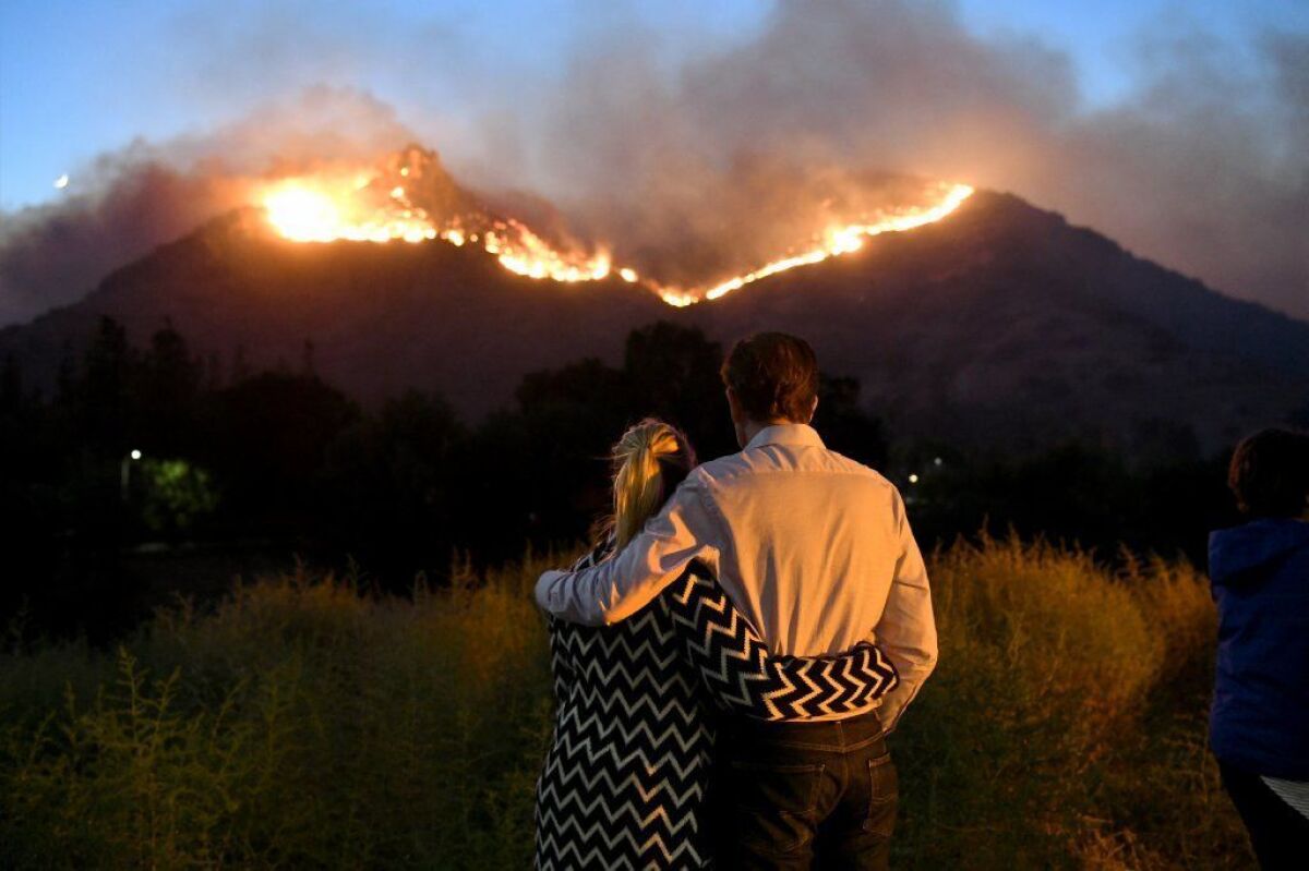 Residents Ann and Roger Bloxberg watch the Woolsey fire at the mouth of Bell Canyon.