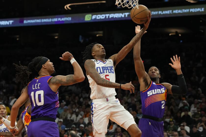 Los Angeles Clippers guard Bones Hyland (5) drives between Phoenix Suns guard Damion Lee and Phoenix Suns forward Josh Okogie (2) during the second half of an NBA basketball game, Sunday, April 9, 2023, in Phoenix. The Clippers won 119-114. (AP Photo/Rick Scuteri)