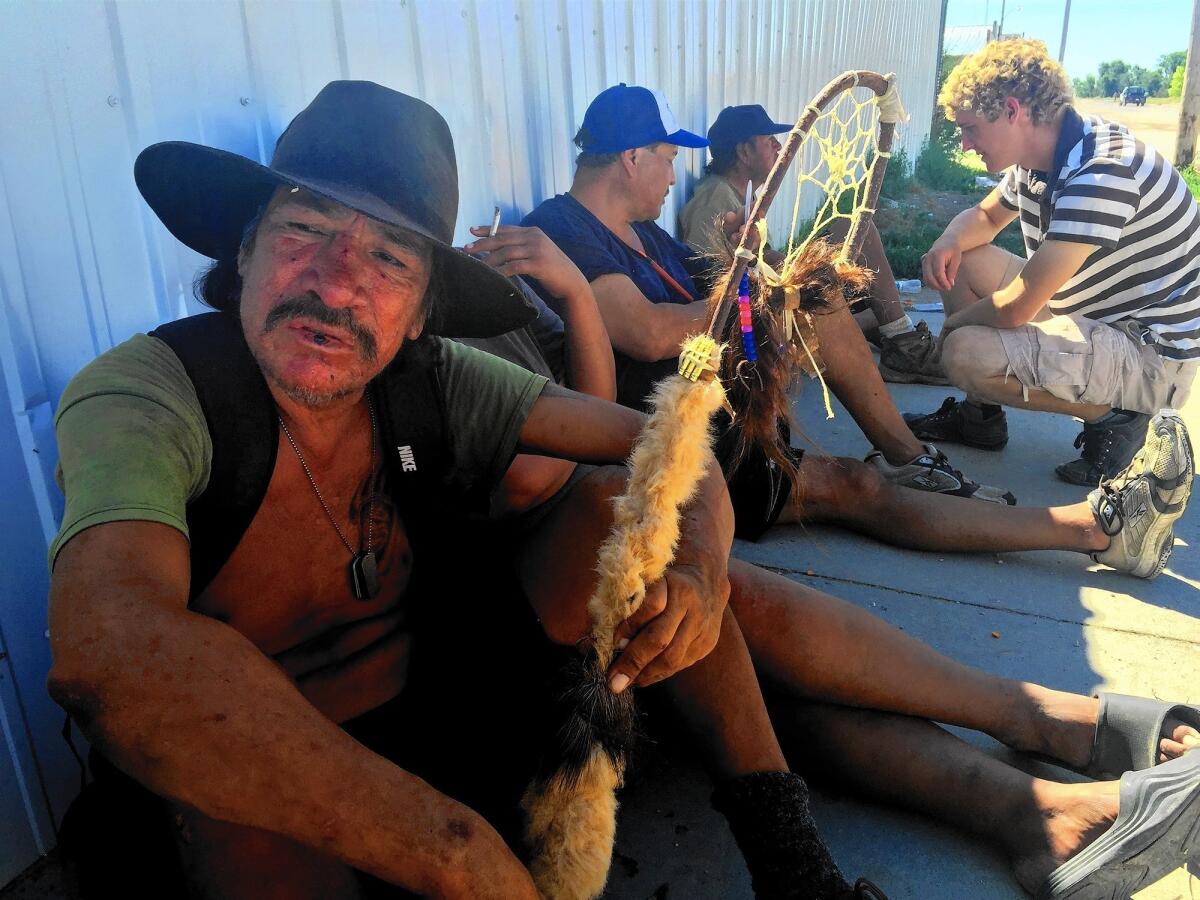 Harley Dreamer lives on the streets of Whiteclay, Neb. He says he is a descendant of Crazy Horse, but he's unable to quit drinking. Abram Neumann, 20, at right, talks to men sitting with Dreamer.
