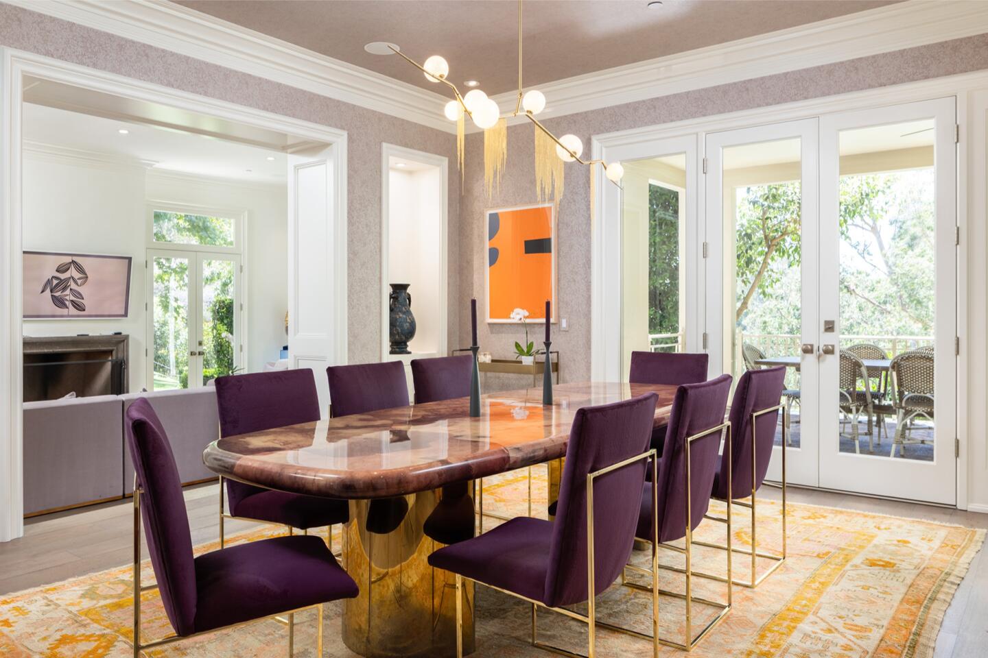 The dining room has a table and chairs with windows overlooking greenery.