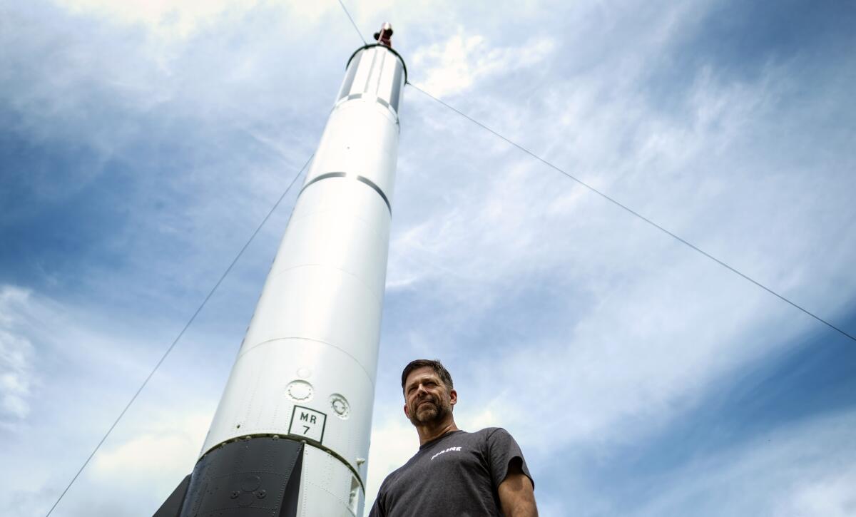 A man stands next to a model of a rocket.