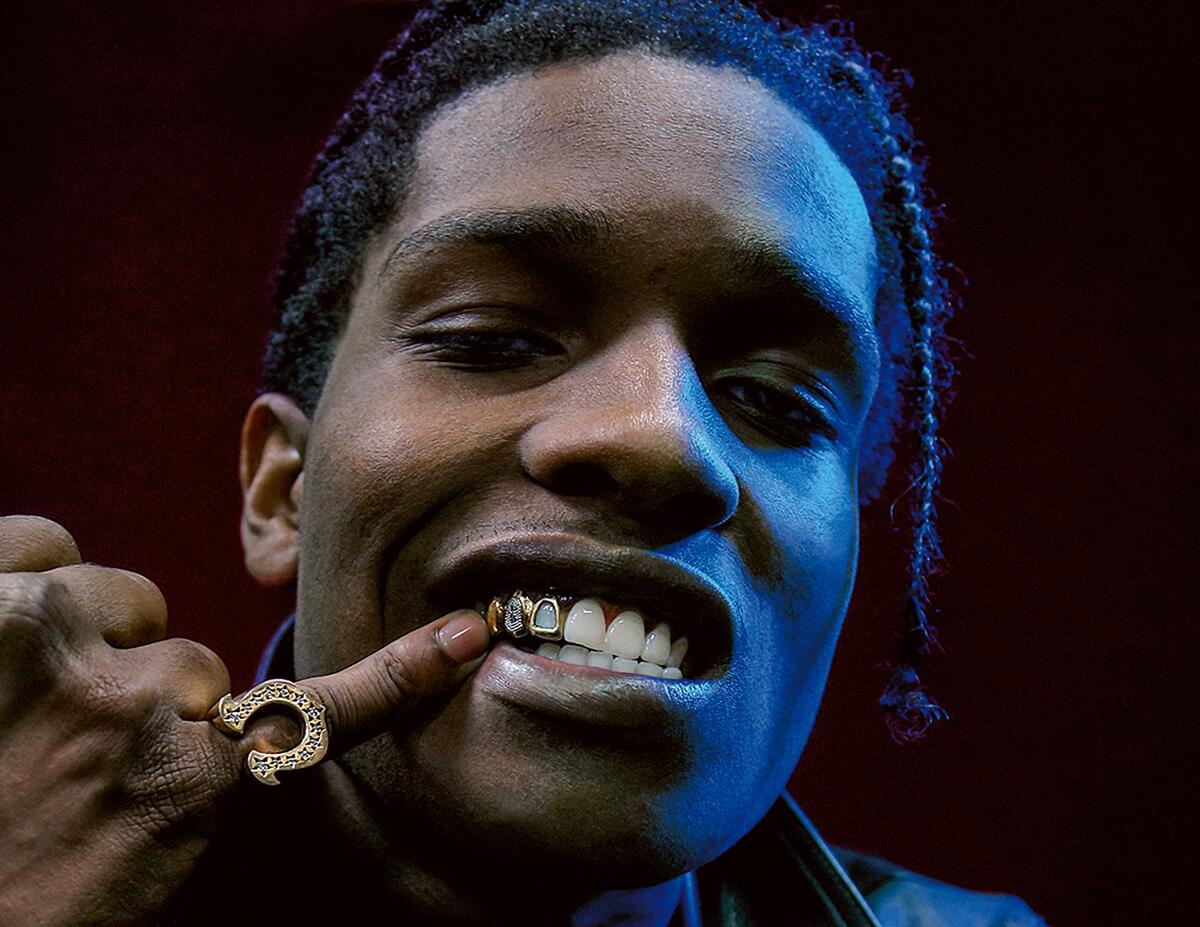 A man uses a ring-adorned little finger to point to his gold grill.