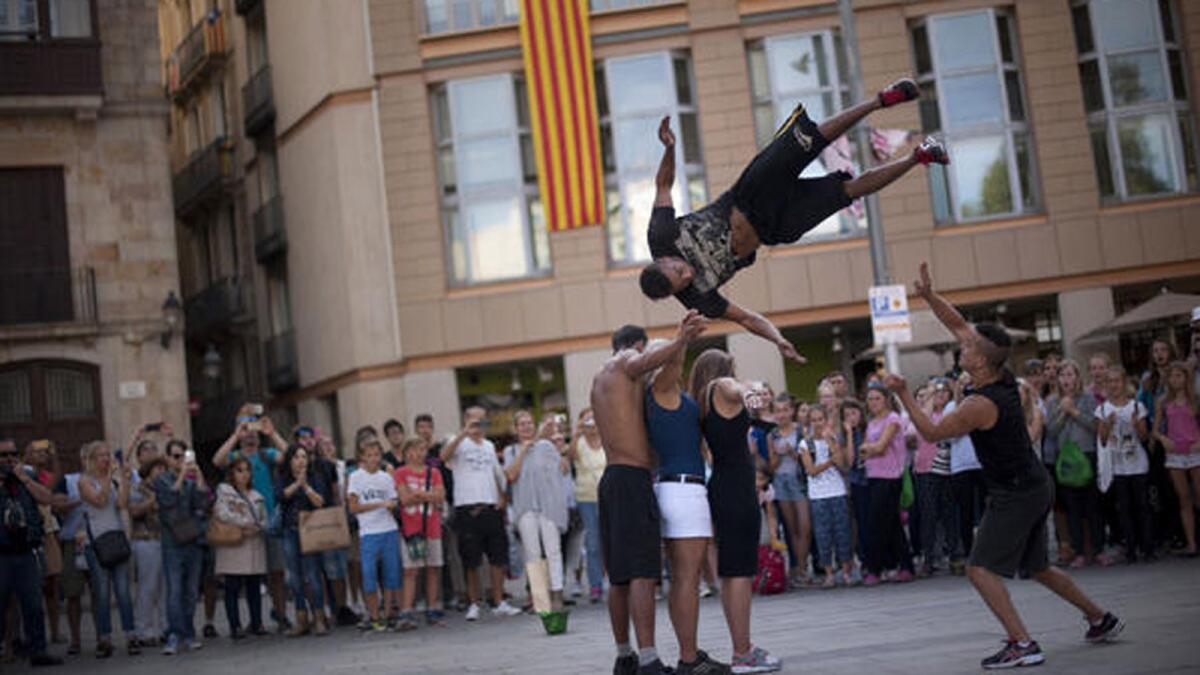 Acrobats perform in the street as a pro-independence Catalan flag hangs in the background on the eve of the Catalan regional election.