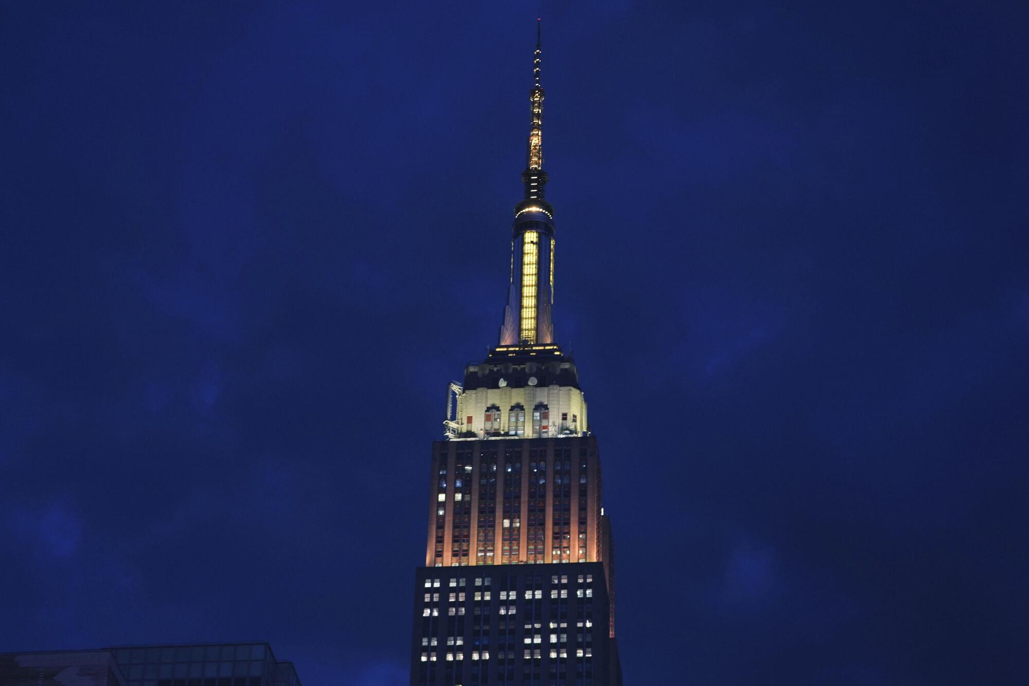 The Empire State Building is lit in gold and white