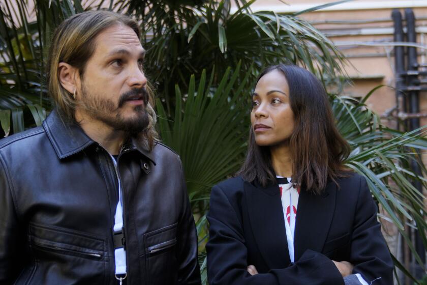 La actriz estadounidense Zoe Saldana mira a su esposo y al director de cine Marco Perego durante la vista previa para la prensa dentro de la prisión de mujeres en la isla Giudecca durante la 60a Bienal de Artes en Venecia, Italia.