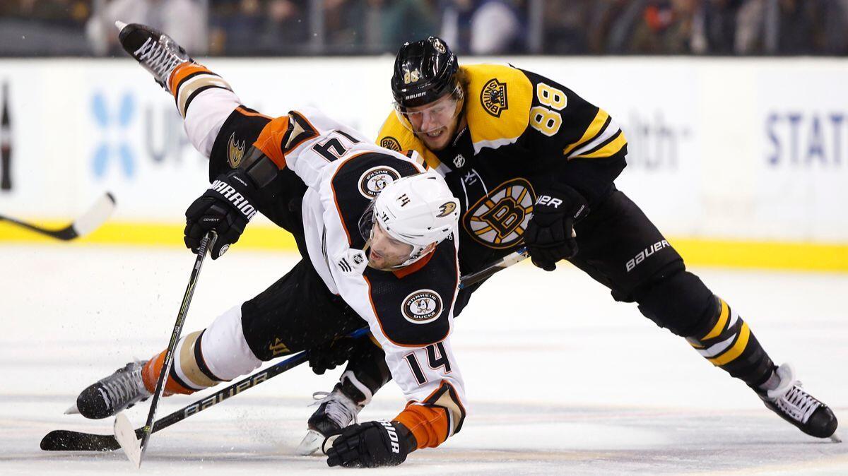 Ducks' Adam Henrique (14) is sent to the ice by Boston Bruins' David Pastrnak during the third period on Tuesday.