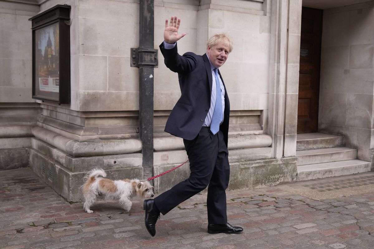 Britain's Prime Minister Boris Johnson waves at the media as he leaves with his dog Dilyn after voting at a polling station in London, for local council elections, Thursday, May 5, 2022. (AP Photo/Matt Dunham)