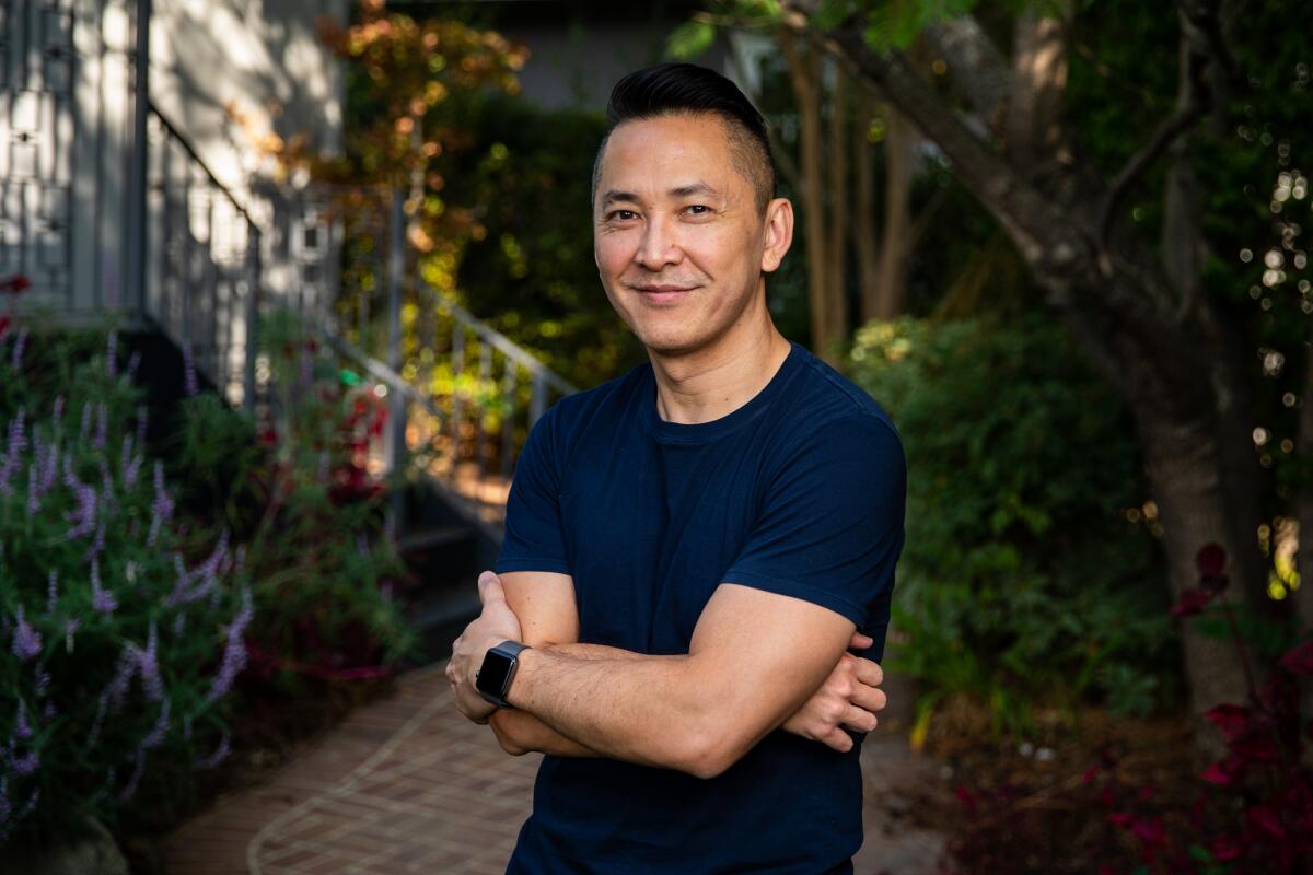 Viet Thanh Nguyen is shown standing, arms crossed, in his garden.