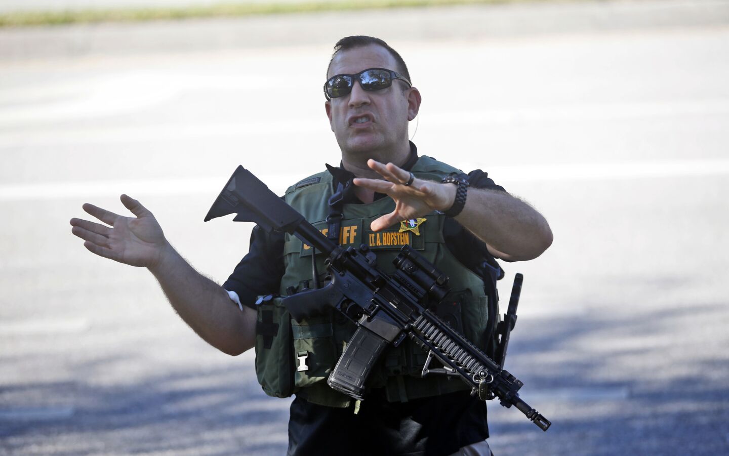 A law enforcement officer tells anxious family members to move back after a shooting at Marjory Stoneman Douglas High School in Parkland, Fla.