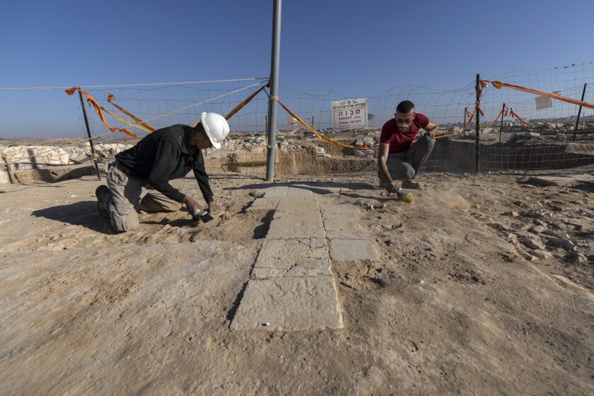 Two people on their knees in dirt.