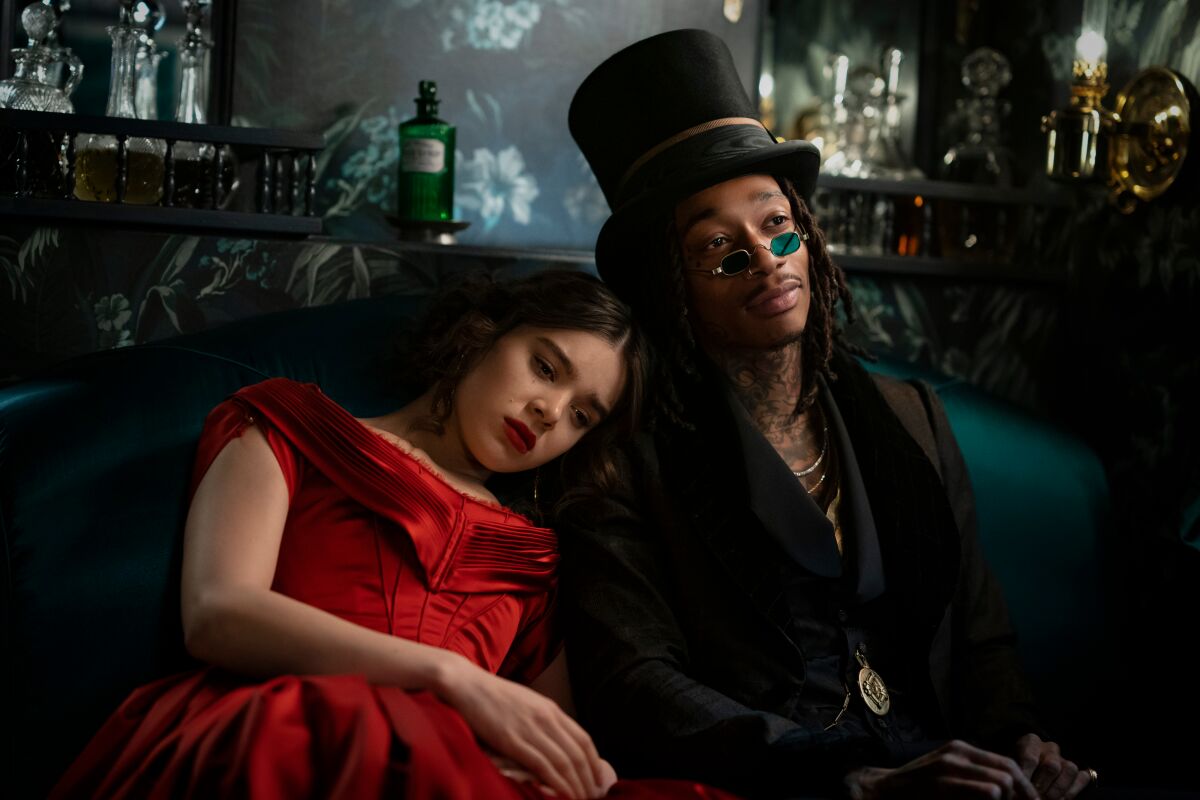 Hailee Steinfeld and Wiz Khalifa relax on a couch in "Dickinson."