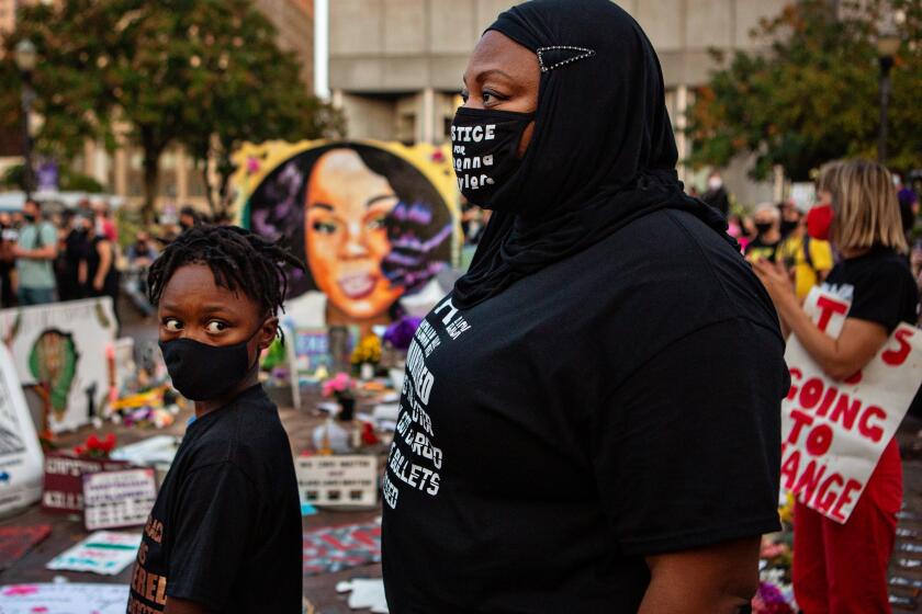 LOUISVILLE, KY - SEPTEMBER 26: A mother and son attends a demonstration in what is now called Injustice Square Park in downtown Louisville along with hundreds of others protesting a Kentucky grand jury's indictment of one of three police officers in the killing of Breonna Taylor, but not for her death on Saturday, Sept. 26, 2020 in Louisville, KY. (Jason Armond / Los Angeles Times)