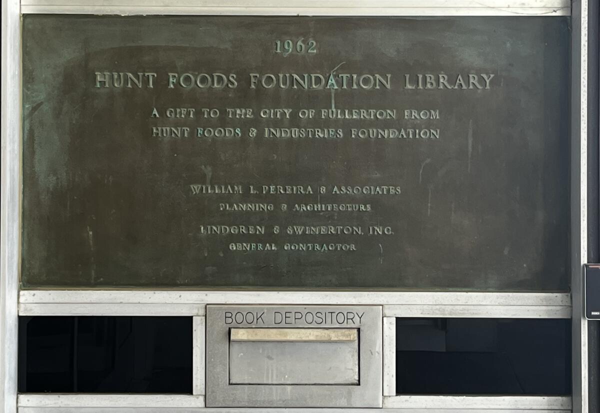 A book depository sits below a dedication plaque outside of the Hunt Branch Library in Fullerton.