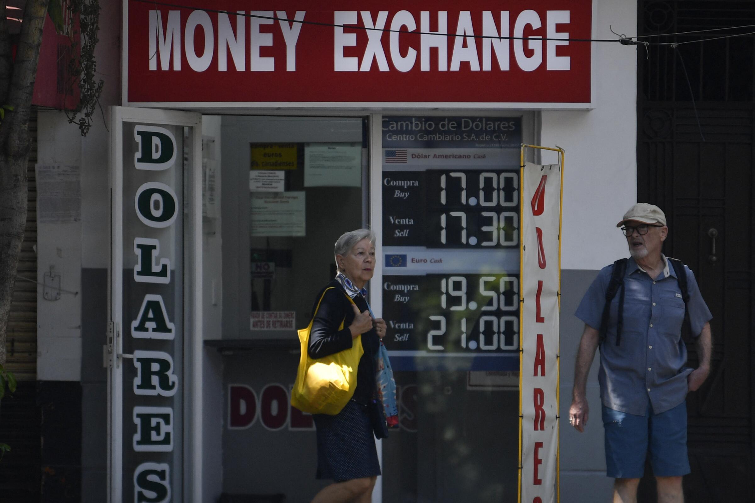 A woman walks past a money exchange in Mexico City