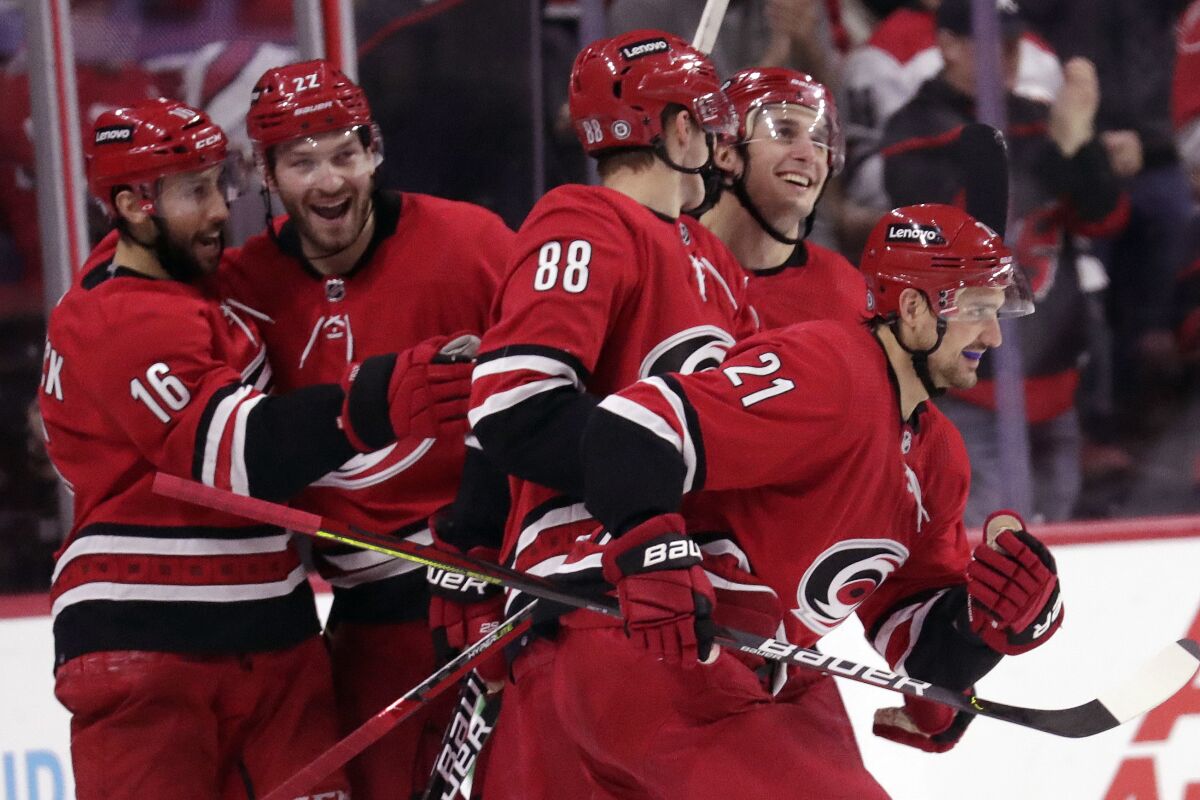 Carolina Hurricanes right wing Nino Niederreiter (21) celebrates his second goal of the night with teammates center Vincent Trocheck (16), defenseman Brett Pesce, second from left, Martin Necas (88) and defenseman Tony DeAngelo, second from right, during the third period of an NHL hockey game against the Detroit Red Wings, Thursday, Dec. 16, 2021, in Raleigh, N.C. (AP Photo/Chris Seward)