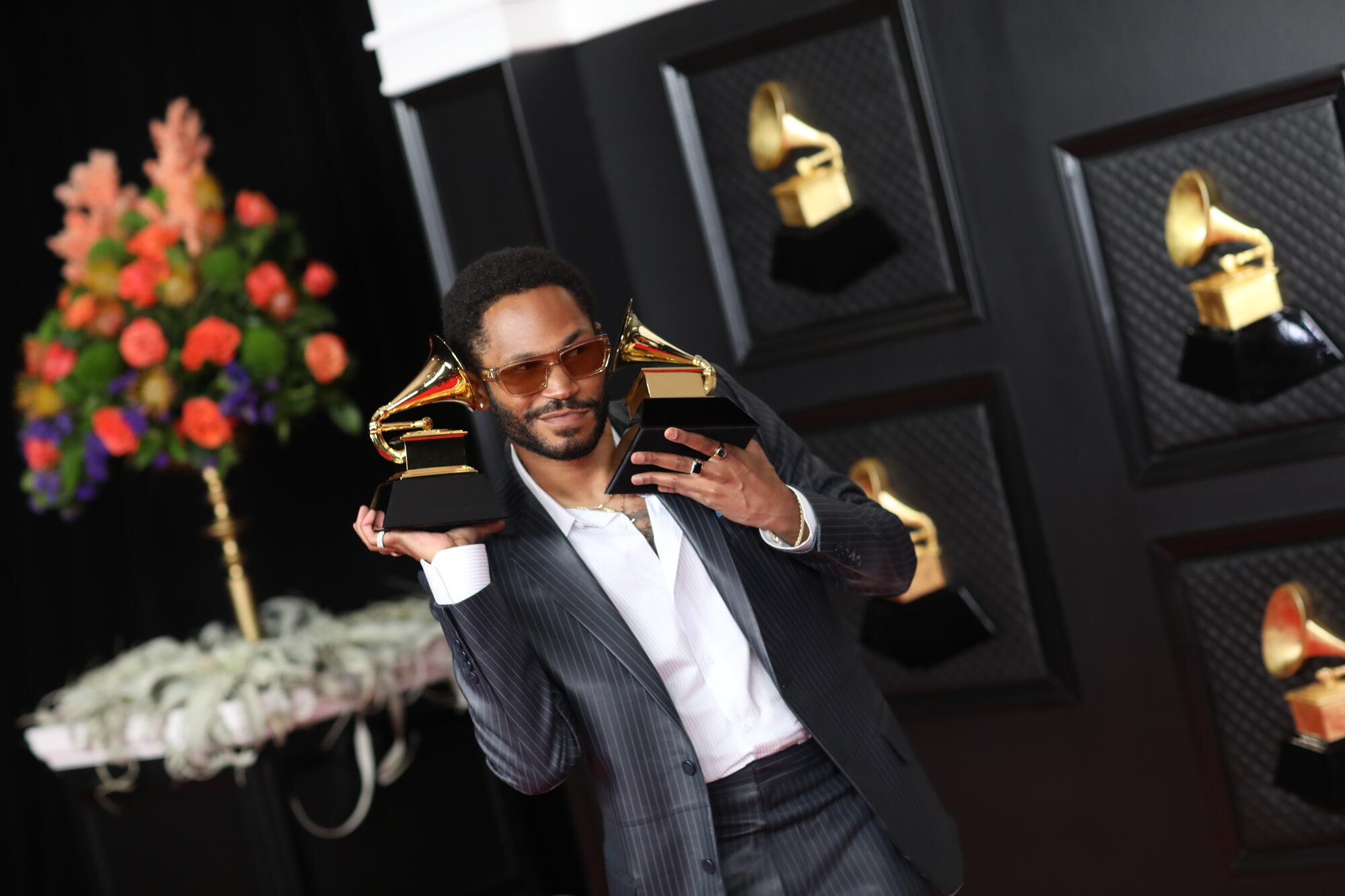 Kaytranada holds one Grammy to each ear.