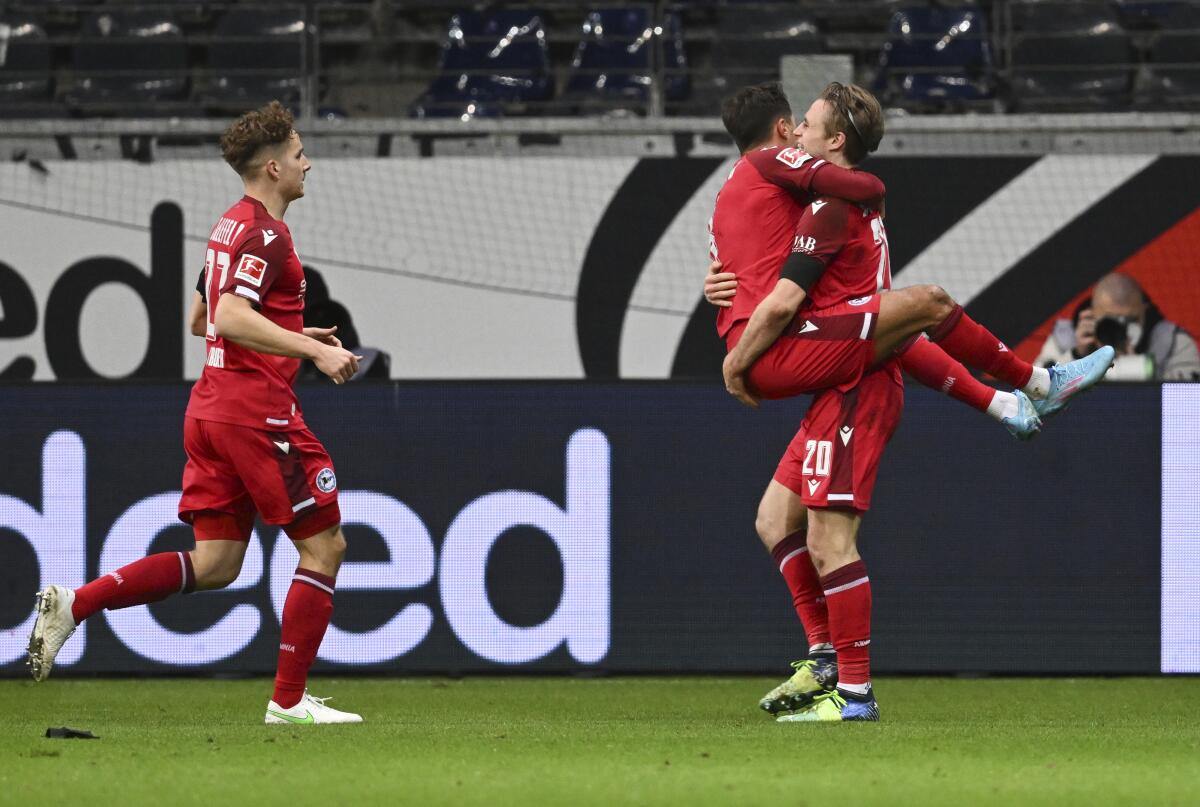 Bielefeld's Alessandro Schopf, second right, celebrates scoring with teammate Patrick Wimmer, right, and Cedric Brunner during the Bundesliga soccer match between Eintracht Frankfurt and Arminia Bielefeld at Deutsche Bank Park, Frankfurt, Germany, Friday Jan. 21, 2022. (Arne Dedert/dpa via AP)