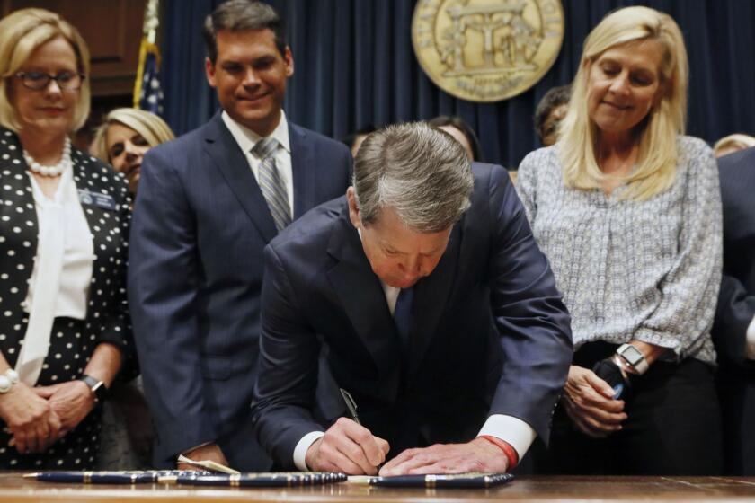 FILE - In this May 7, 2019, file photo, Georgia's Republican Gov. Brian Kemp, center, signs legislation in Atlanta, banning abortions once a fetal heartbeat can be detected, which can be as early as six weeks before many women know they're pregnant. Georgia became the fourth state to enact the ban on abortions after a fetal heartbeat can be detected. (Bob Andres/Atlanta Journal-Constitution via AP, File)
