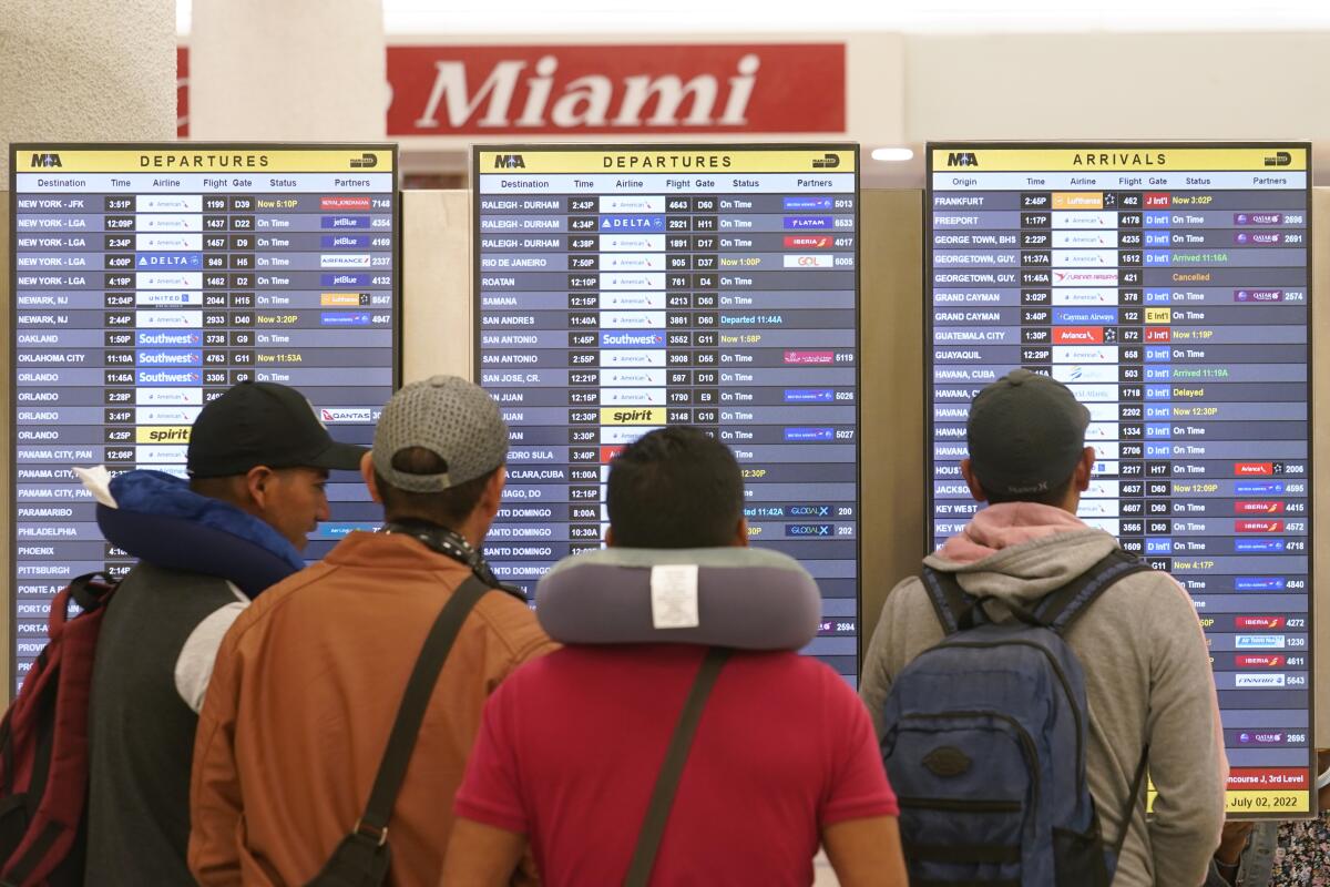 Travelers check their flights at Miami International Airport, Saturday, July 2, 2022, in Miami. The Fourth of July holiday weekend is jamming U.S. airports with the biggest crowds since the pandemic began in 2020. (AP Photo/Marta Lavandier)