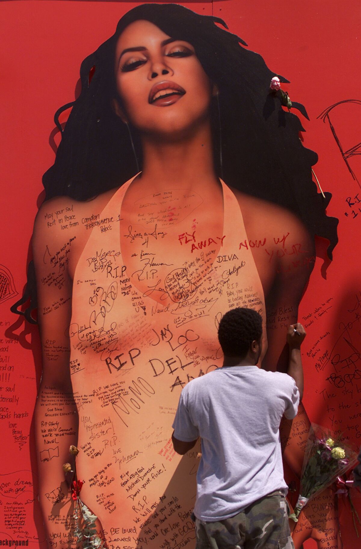 A fan writes a message on a billboard at Tower Records in Hollywood on Sunset Boulevard promoting Aaliyah’s 2001 album after the singer’s tragic death.