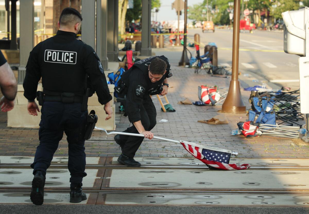A police officer picks up an American flag left behind at a mass shooting.