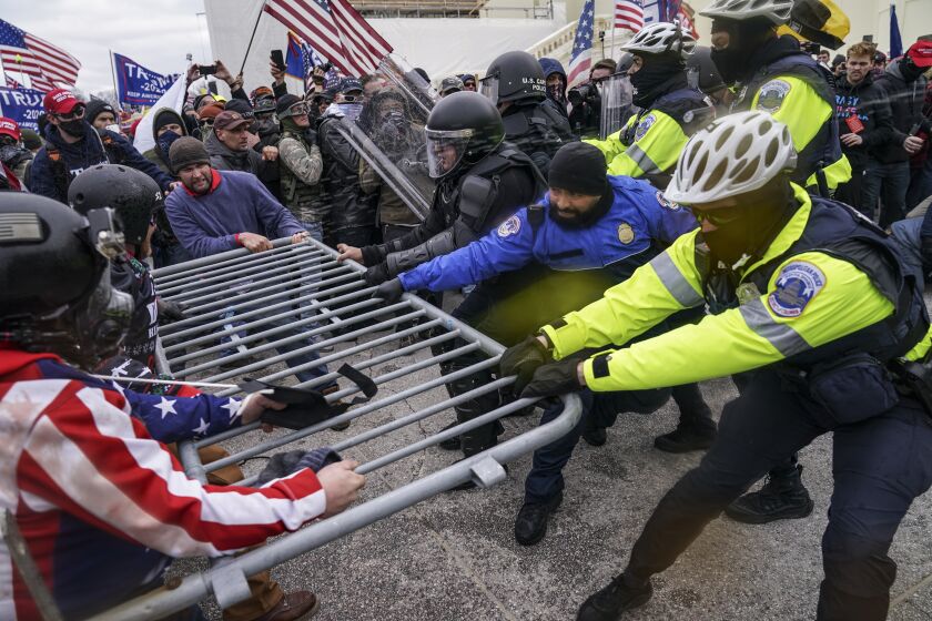 FILE - In this Jan. 6, 2021, file photo violent insurrectionists loyal to President Donald Trump supporters try to break through a police barrier at the Capitol in Washington. A month ago, the U.S. Capitol was besieged by Trump supporters angry about the former president's loss. While lawmakers inside voted to affirm President Joe Biden's win, they marched to the building and broke inside. (AP Photo/John Minchillo, File)