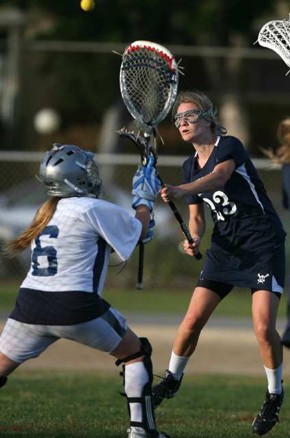 Newport Harbor's Sierra Michaelsen, right, shoots past Corona del Mar goalie Kassie Colombo to score during the Battle of the Bay lacrosse match at Newport Harbor High School on Friday.