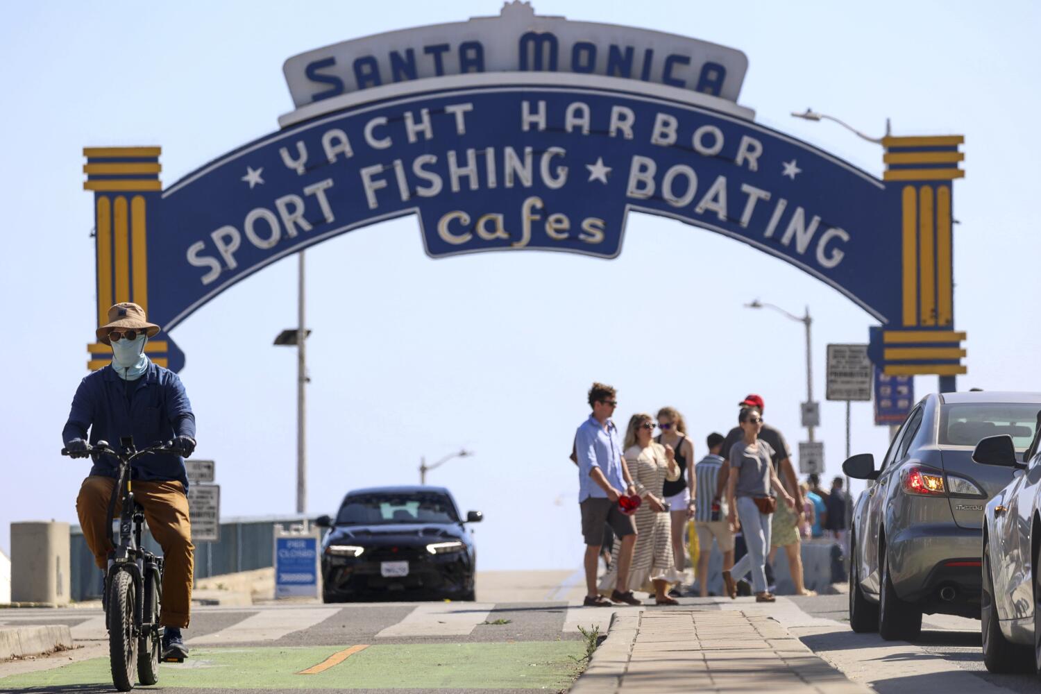 Los Angeles, CA - June 25: A pedestrian rides a bike on Colorado Ave near Santa Monica Pier on Tuesday, June 25, 2024 in Los Angeles, CA. (Zoe Cranfill / Los Angeles Times)