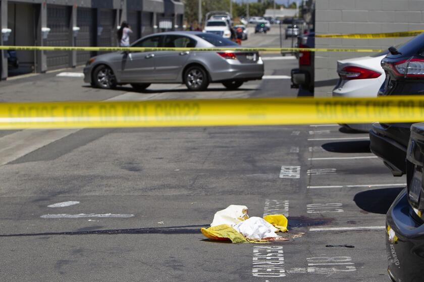 Blood stains the pavement in a parking lot where a person was shot Monday morning at the Breakwater Apartments in Huntington Beach.