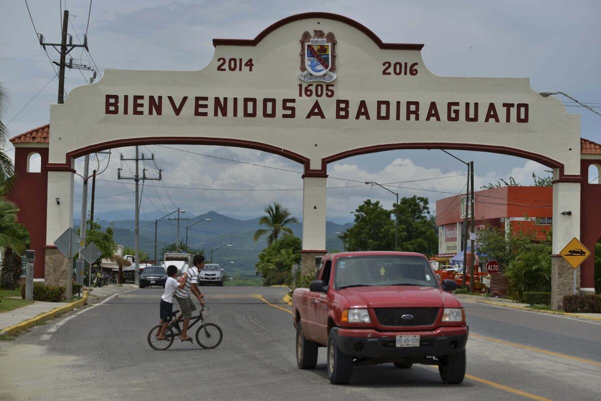 En esta imagen del 20 de julio de 2015, un auto pasa junto a la entrada de Badiraguato, México. Incrustado en las pequeñas colinas donde los tramos costeros de campos de maíz y tomate se unen a las imponentes montañas de la Sierra Madre, Badiraguato sigue sumido en la pobreza.