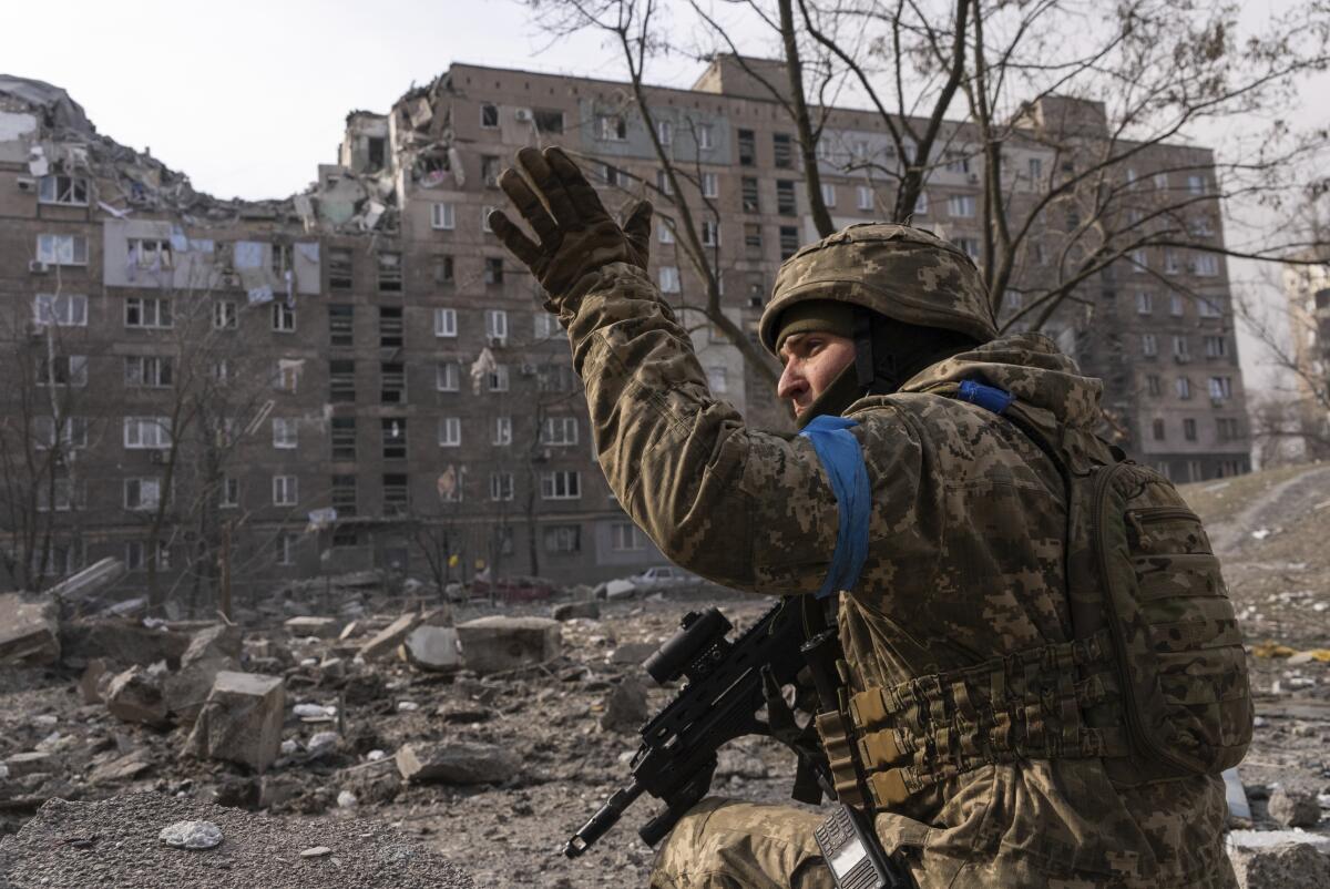Ukrainian serviceman outside damaged building in Mariupol
