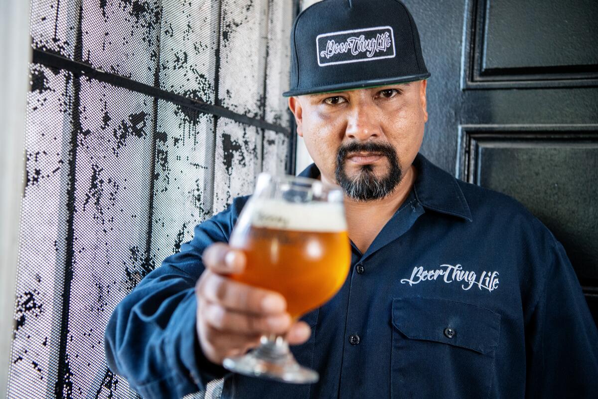 Edgar Preciado holds out a tulip glass of beer.