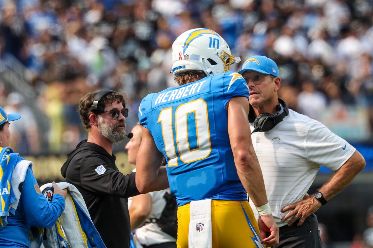 Chargers quarterback Justin Herbert talks with coach Jim Harbaugh on the sideline during a win over the Raiders on Sept. 8.