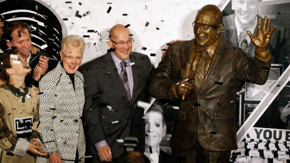 A statue honoring former Los Angeles Kings broadcaster Bob Miller is unveiled in Star Plaza outside Staples Center, as Miller stands with his wife, Judy Miller, third from left, and other family members before the Kings' game against the Anaheim Ducks in Los Angeles.