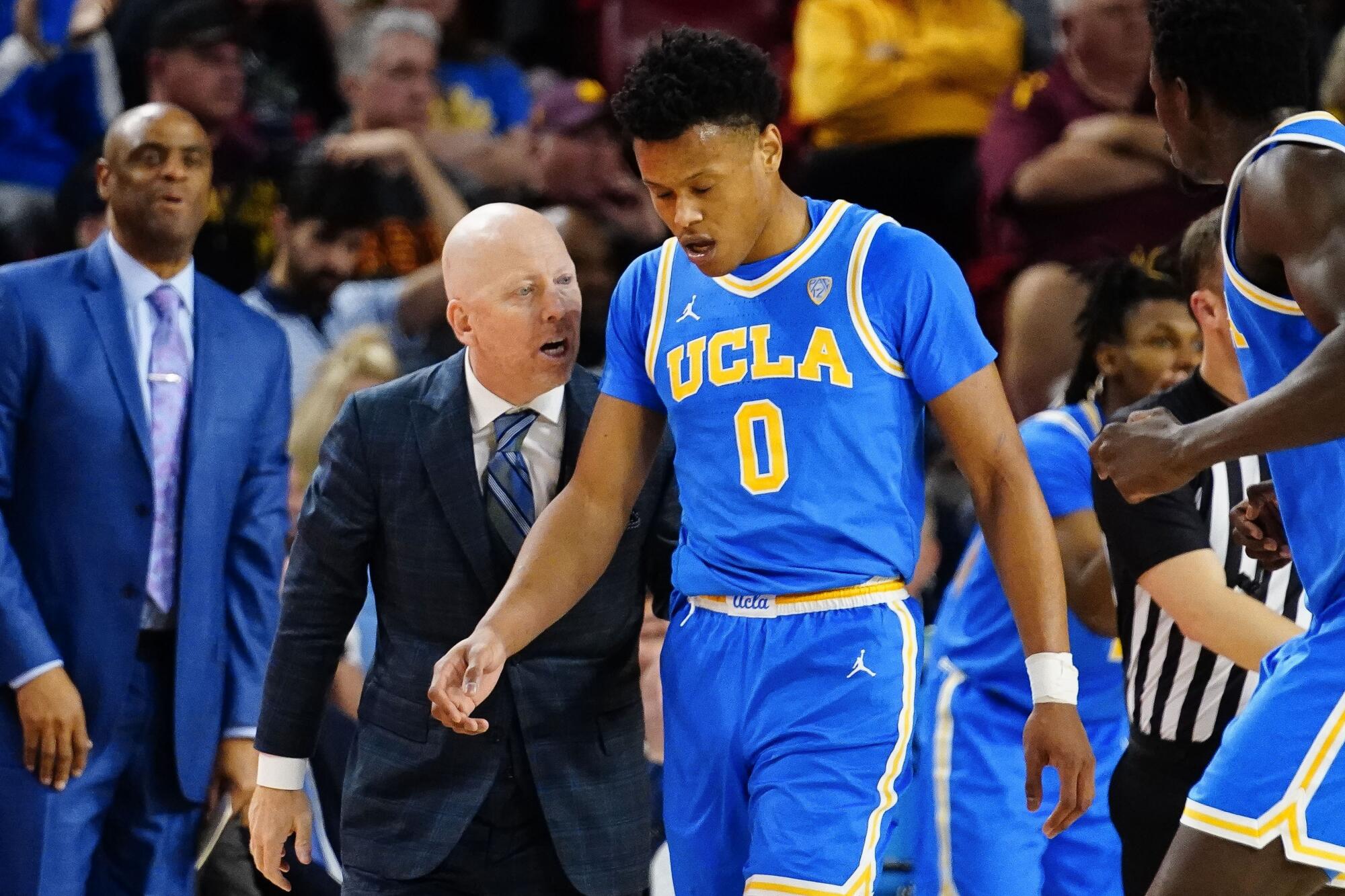 UCLA coach Mick Cronin stands on the sideline and gives Jaylen Clark instructions as the player walks by 