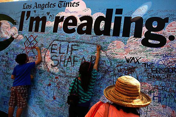 Robert Lewis, 12, from left, Clara Cohen, 12, and her mother Lynn Cohen, write what they are currecntly reading on a canvas on the side of the LA Times tent during the Los Angeles Times Festival of Books at USC in Los Angeles on April 22, 2012. ()