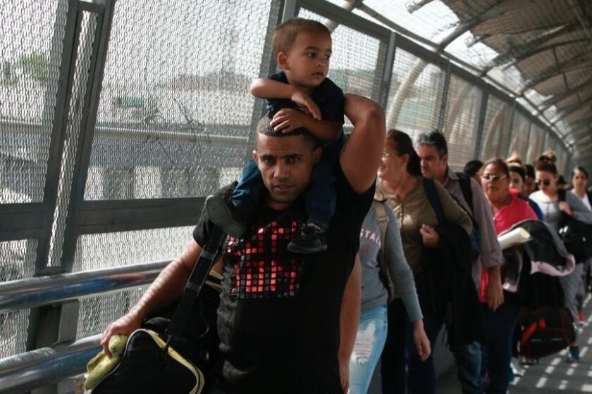In this April 29, 2019, photo, Cuban migrants are escorted by Mexican immigration officials in Ciudad Juarez, Mexico, as they cross the Paso del Norte International bridge to be processed as asylum seekers on the U.S. side of the border. Burgeoning numbers of Cubans are trying to get into the U.S. by way of the Mexican border, creating a big backlog of people waiting on the Mexican side for months for their chance to apply for asylum. (AP Photo/Christian Torres)