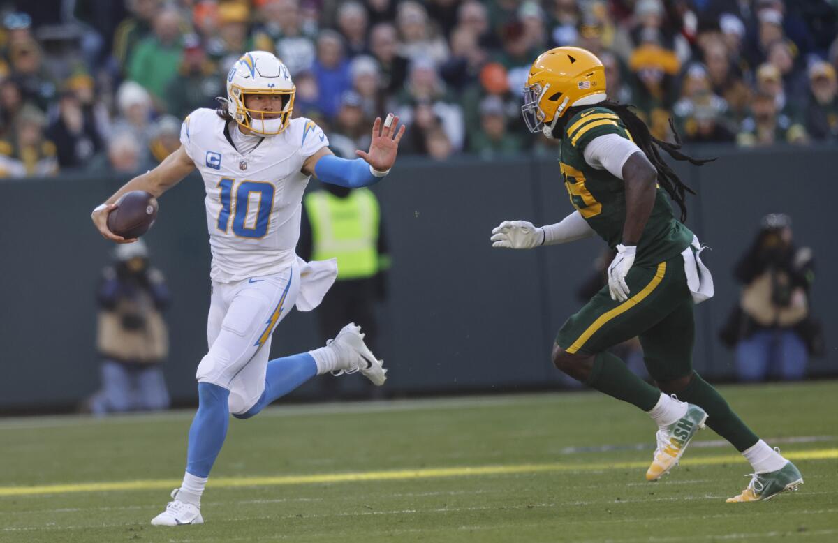 Chargers quarterback Justin Herbert scrambles against a Packers opponent.