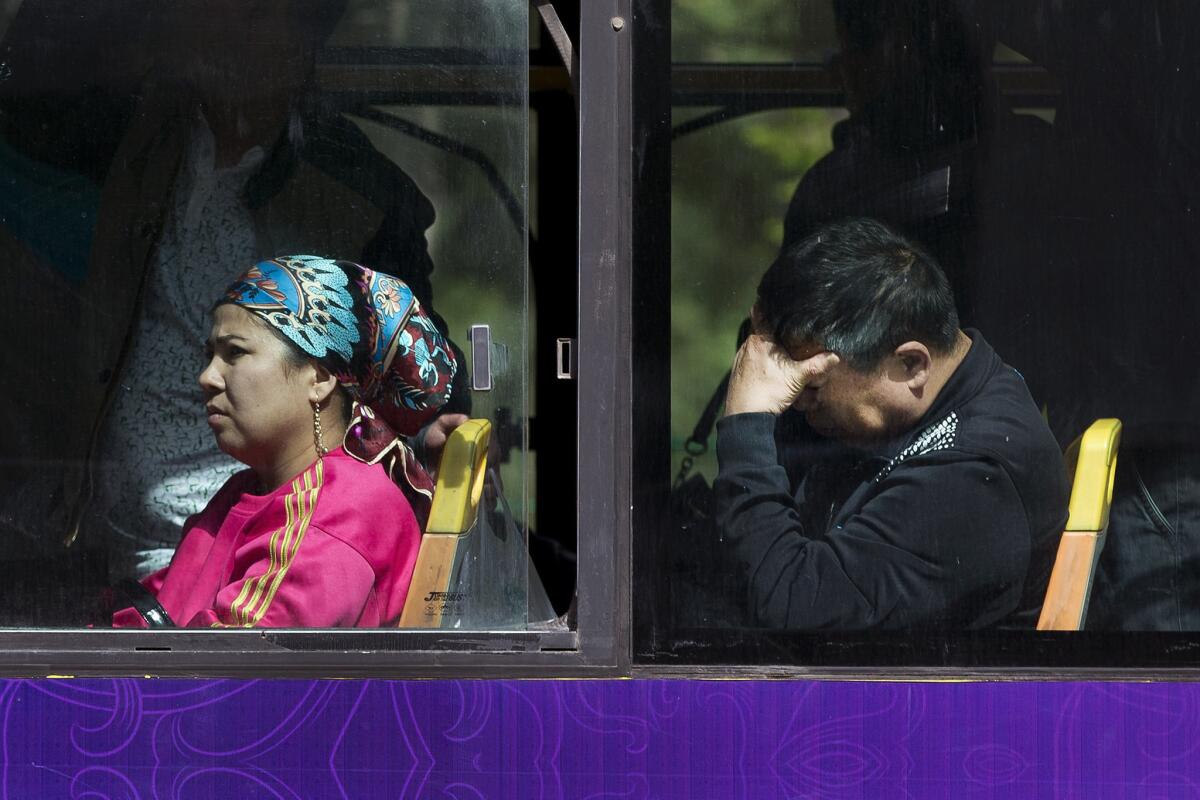 A Chinese man sits behind a Uighur woman on a public bus in Urumqi, in China's northwestern region of Xinjiang, on May 23, 2014.