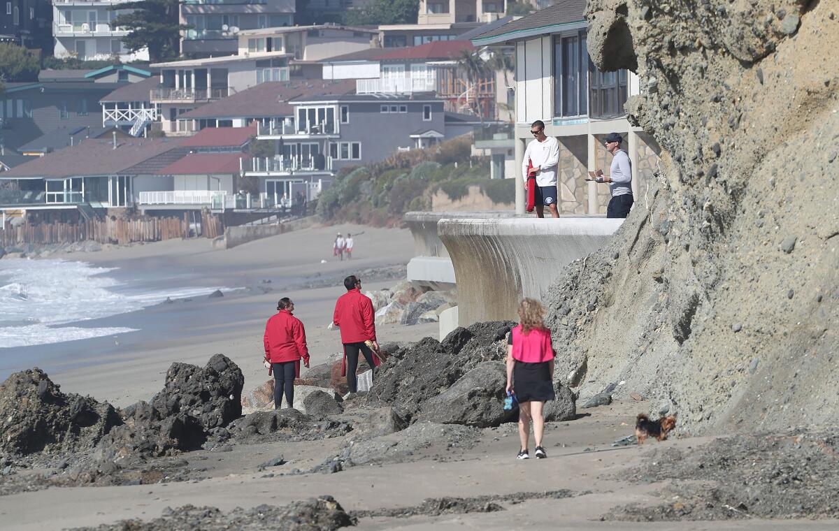 Lifeguards walk along the Lagunita seawall near where a boat ran aground in Laguna Beach.