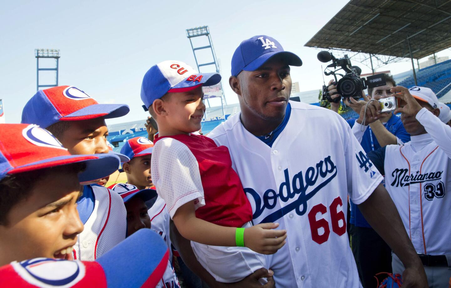 Los Angeles Dodgers player Yasiel Puig, from Cuba, holds a young baseball player as he poses for photos before giving a baseball clinic to children in Havana, Cuba, Wednesday, Dec. 16, 2015. "We're going to give our best on this visit and we appreciate the opportunity we've been given," said Puig, who left Cuba on a smuggler's fast-boat in 2012. "Everything else we leave to God and destiny." (AP Photo/Ramon Espinosa)