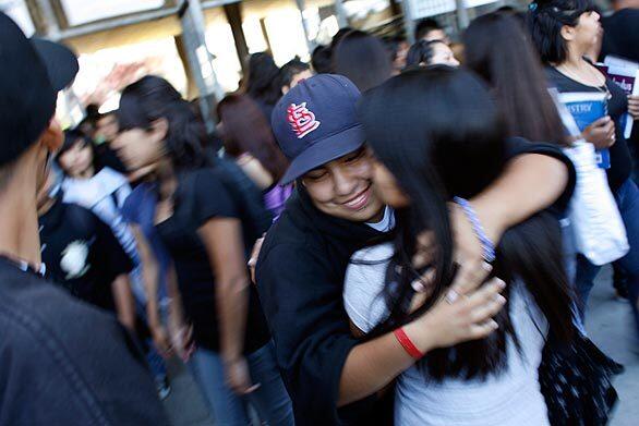 Karla Valencia, 17, is embraced by a friend outside Santee High School in South Los Angeles, where she hopes to return after studying at a small charter school on Manchester Avenue run by the nonprofit Soledad Enrichment Action. Group therapy sessions run by Stan Bosch, a Catholic priest, have helped her.