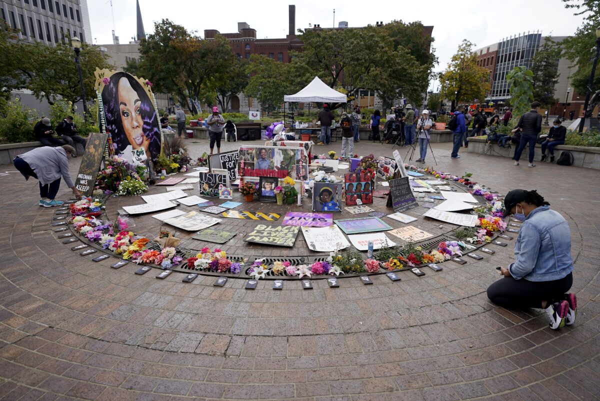 A woman kneels in front of a makeshift memorial in honor of Breonna Taylor in Louisville, Ky.