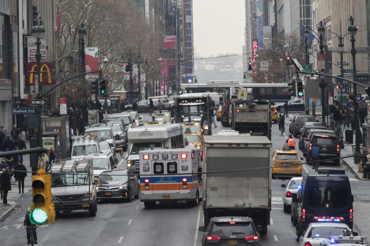 Buses, trucks, cars, cabs and an ambulance in city traffic.