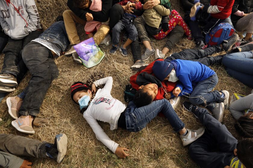 LA JOYA, TEXAS - March 25, 2021— Asylum seekers, including minors and babies, sleep on the ground while waiting for over 12 hours to be bused to Border Patrol facilities where they will be processed. Photograph taken on March 25, 2021. (Carolyn Cole / Los Angeles Times)