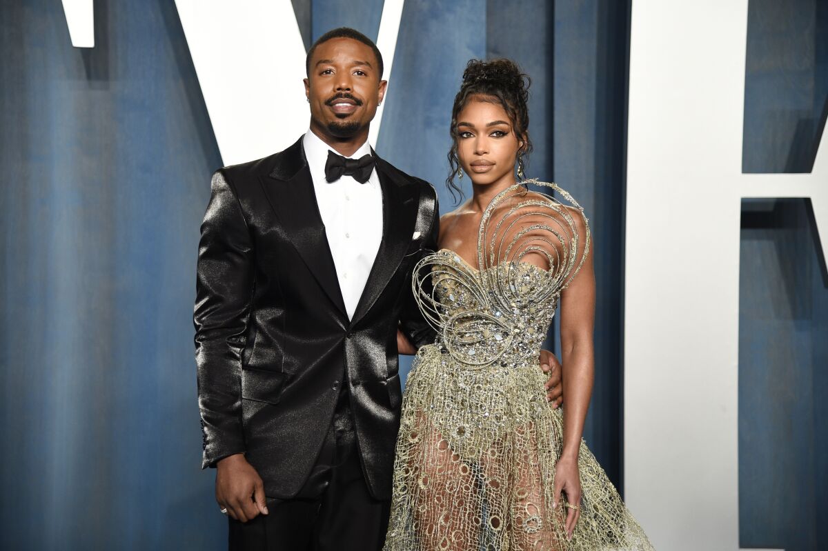 A man in a tuxedo put his arm around a woman in a strapless evening gown.