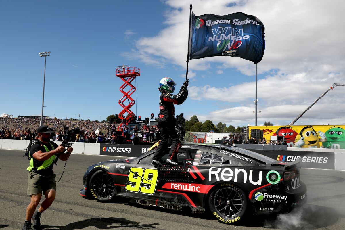 Daniel Suárez waves a flag celebrating his first NASCAR Cup win Sunday at Sonoma Raceway.